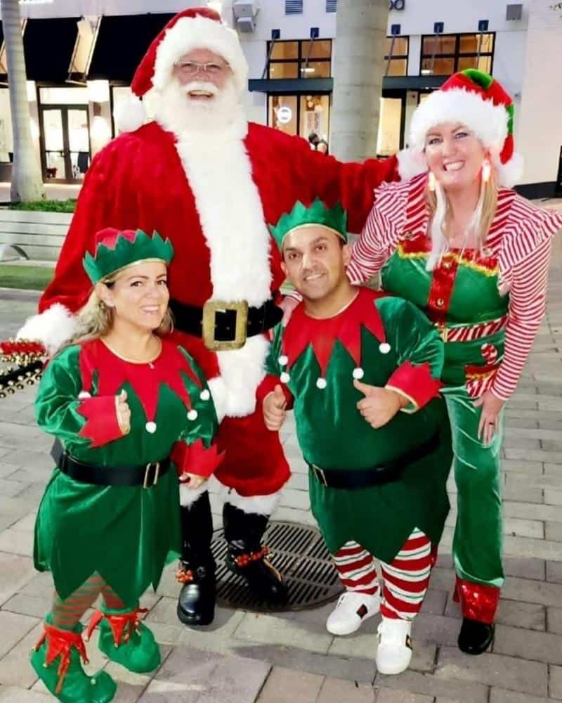 Rent a Santa near me in Atlanta: Santa with three elves in green costumes and hats.
